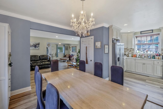 dining area featuring light wood-style flooring, baseboards, a chandelier, and ornamental molding