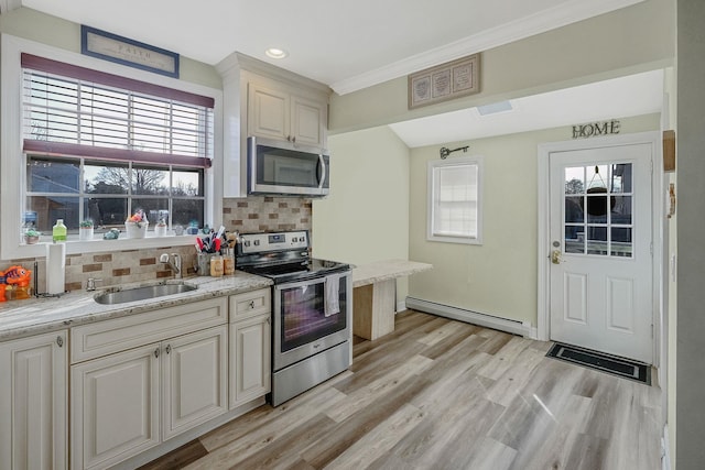 kitchen with light wood finished floors, a baseboard radiator, a sink, appliances with stainless steel finishes, and tasteful backsplash