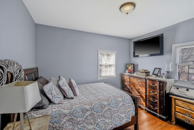 bedroom with light wood finished floors and multiple windows