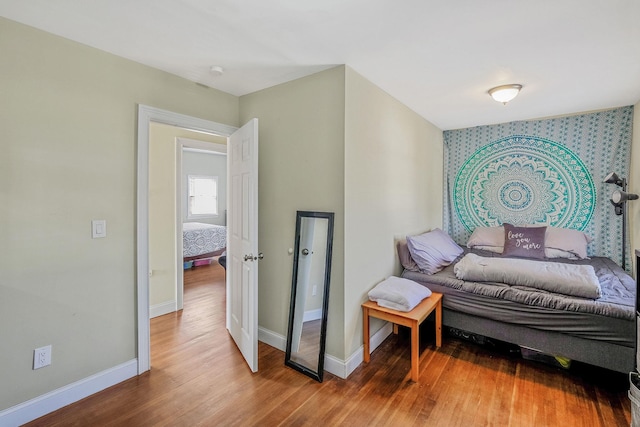 bedroom with baseboards, wood finished floors, and wallpapered walls