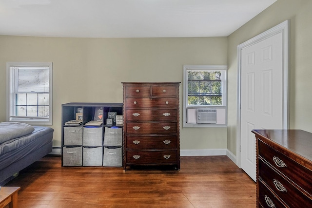 bedroom with baseboard heating, cooling unit, baseboards, and dark wood-style flooring