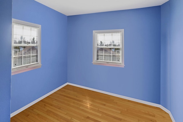 unfurnished room featuring plenty of natural light, baseboards, and hardwood / wood-style floors