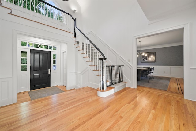 foyer entrance featuring a notable chandelier, stairway, a decorative wall, and wood finished floors