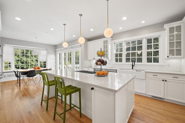 kitchen with light wood-type flooring, a center island, visible vents, and a sink