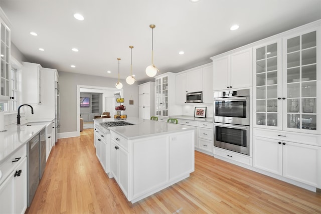 kitchen featuring a sink, stainless steel appliances, a kitchen island, and white cabinets