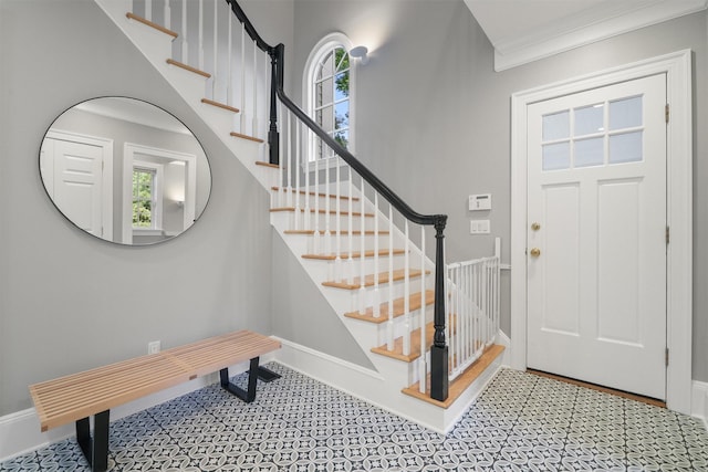 entryway featuring a healthy amount of sunlight, crown molding, stairs, and baseboards