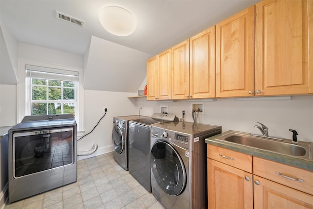 clothes washing area with visible vents, baseboards, washer and clothes dryer, cabinet space, and a sink