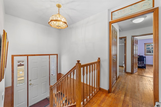 foyer with hardwood / wood-style floors, baseboards, and a chandelier