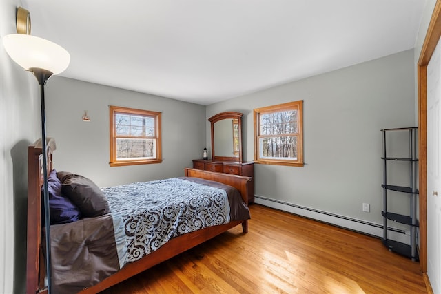 bedroom with baseboard heating and wood finished floors