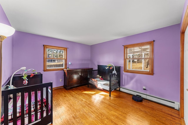 bedroom with wood finished floors and a baseboard radiator