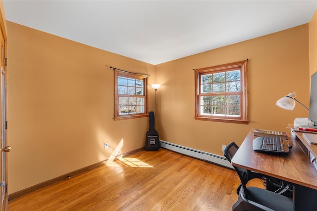 unfurnished office with light wood-type flooring, a baseboard heating unit, and baseboards