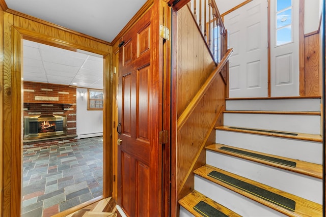 stairway featuring a baseboard heating unit and a brick fireplace