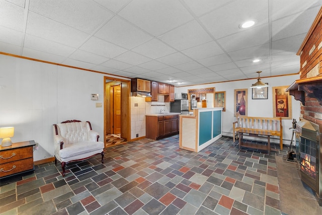 kitchen with a peninsula, a sink, ornamental molding, light countertops, and baseboard heating