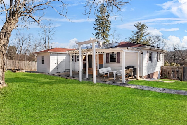 rear view of house featuring a patio area, solar panels, a lawn, and fence