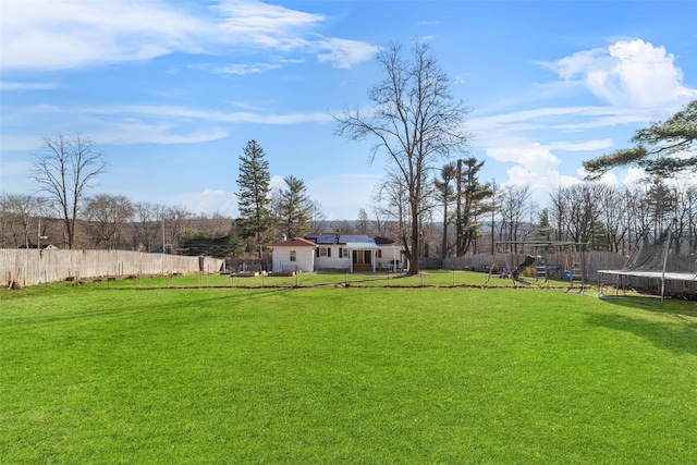 view of yard with playground community, a trampoline, and a fenced backyard