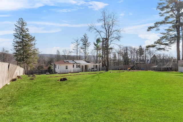 view of yard featuring a fenced backyard, a playground, and a trampoline