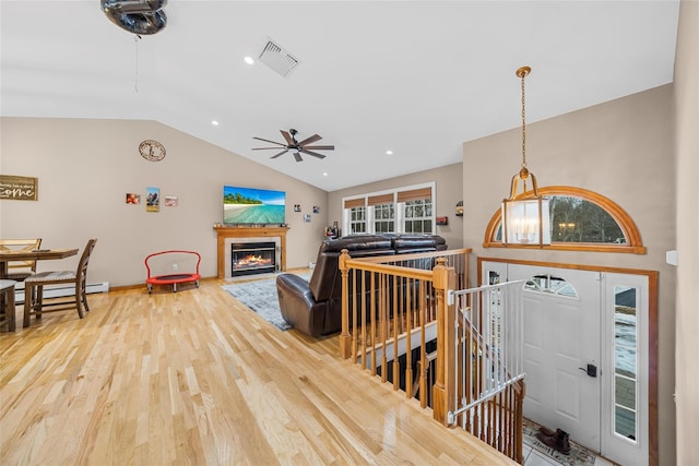 living room featuring wood finished floors, visible vents, a fireplace, ceiling fan, and vaulted ceiling