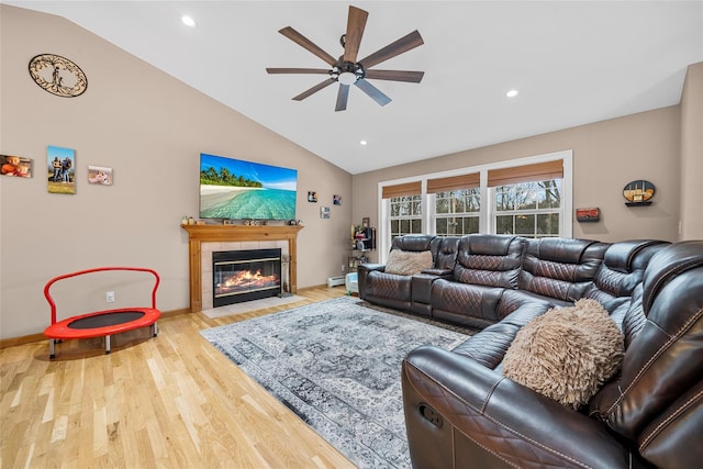 living area featuring a tiled fireplace, lofted ceiling, wood finished floors, and a baseboard heating unit