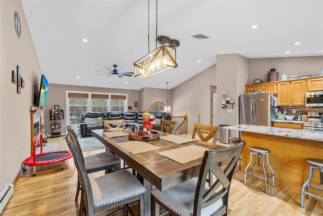 dining area with visible vents, light wood-type flooring, vaulted ceiling, baseboard heating, and ceiling fan with notable chandelier