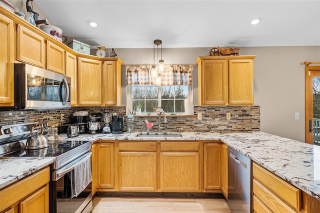 kitchen with decorative backsplash, light stone counters, appliances with stainless steel finishes, and a sink