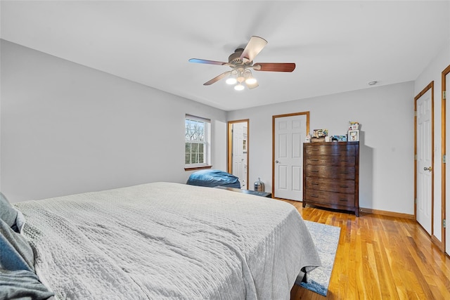 bedroom with light wood finished floors, a ceiling fan, and baseboards