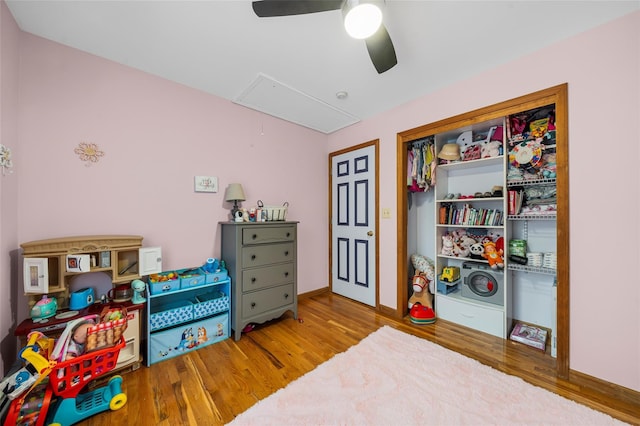 interior space featuring ceiling fan, baseboards, attic access, and wood finished floors