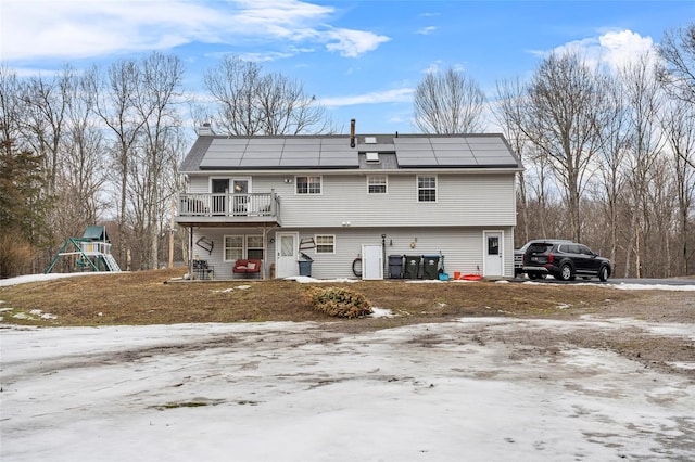 back of property featuring solar panels, a playground, and a wooden deck