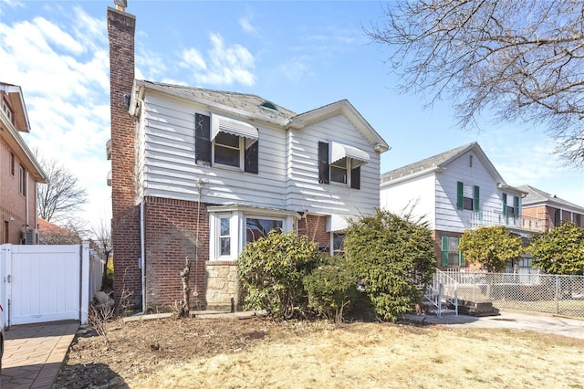 traditional-style home featuring brick siding, a chimney, and fence