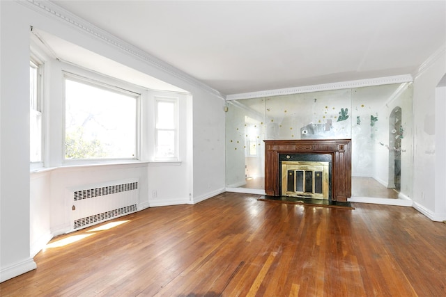 unfurnished living room featuring hardwood / wood-style flooring, a glass covered fireplace, radiator heating unit, arched walkways, and baseboards