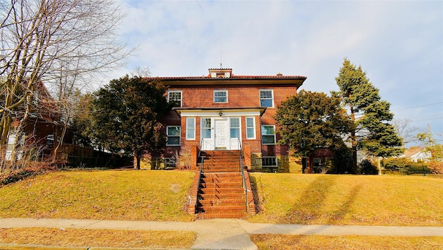 american foursquare style home featuring stairway, fence, a front lawn, and brick siding