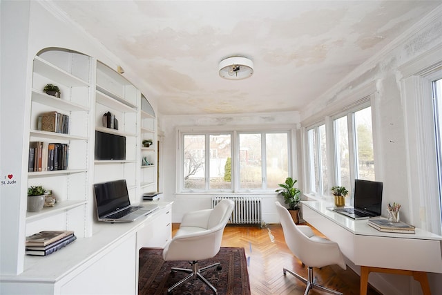 office space with radiator, a healthy amount of sunlight, crown molding, and built in desk