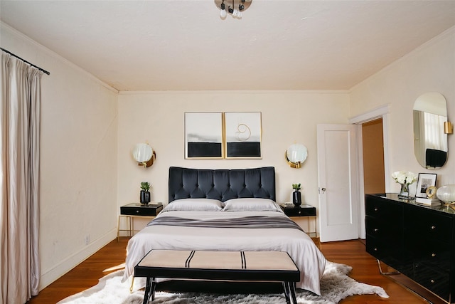 bedroom with baseboards, wood finished floors, and crown molding