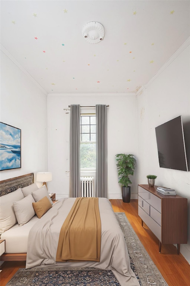 bedroom with ornamental molding, light wood-type flooring, and radiator heating unit