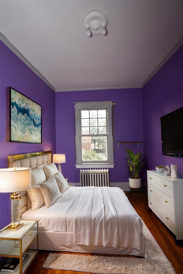 bedroom with radiator, crown molding, and wood finished floors