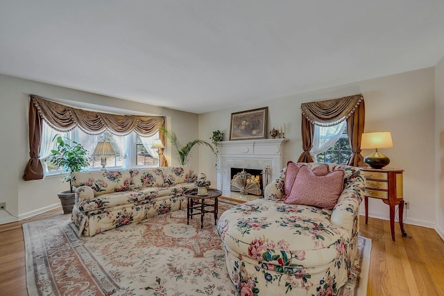 living area with a fireplace with flush hearth, baseboards, and wood finished floors