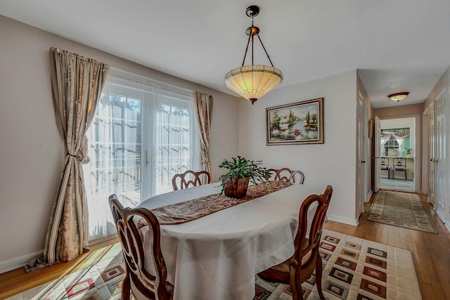 dining area with light wood-type flooring and baseboards