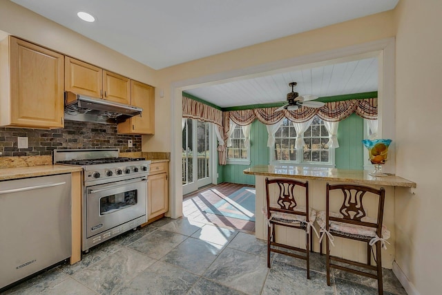 kitchen featuring under cabinet range hood, light countertops, appliances with stainless steel finishes, backsplash, and light brown cabinetry