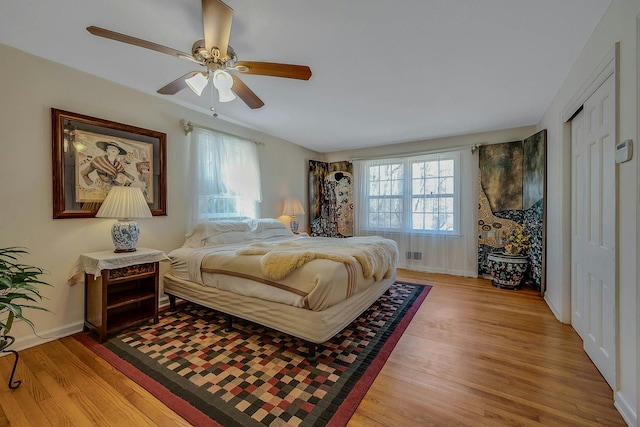 bedroom featuring light wood finished floors, visible vents, and baseboards