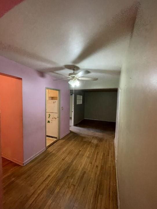 interior space with ceiling fan, wood finished floors, and baseboards