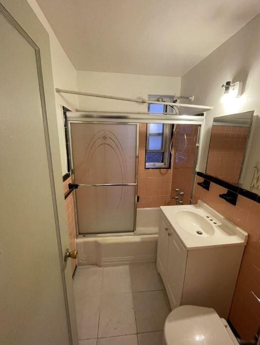 full bath featuring toilet, tile patterned floors, shower / bath combination with glass door, and vanity