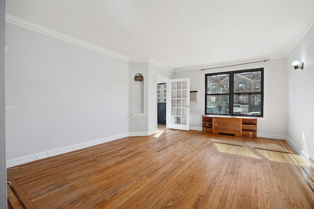 unfurnished room with ornamental molding, light wood-style flooring, and baseboards