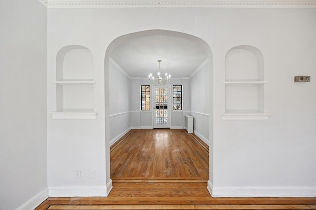 unfurnished dining area with radiator heating unit, built in shelves, baseboards, and a chandelier