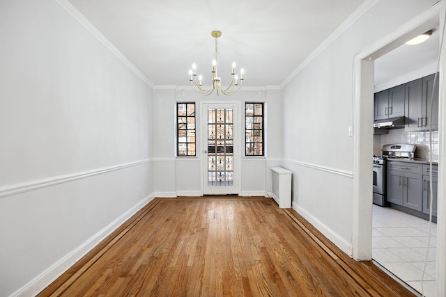 unfurnished dining area featuring a chandelier, ornamental molding, and light wood-type flooring