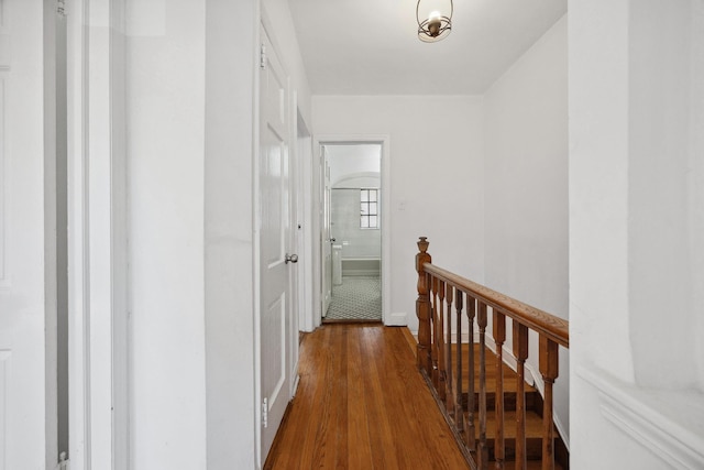 corridor with dark wood-style floors, baseboards, and an upstairs landing