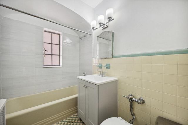 bathroom featuring toilet, a wainscoted wall, vanity, tile walls, and shower / bathing tub combination