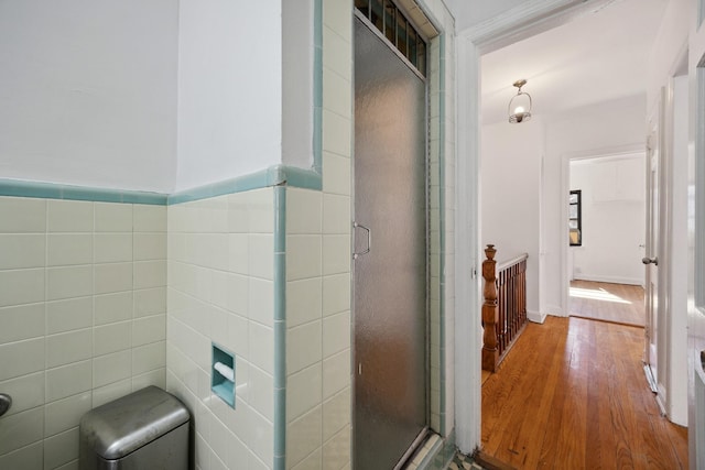 full bathroom featuring tile walls, a shower stall, and wood finished floors