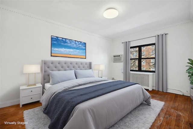 bedroom with radiator, a wall unit AC, baseboards, and wood finished floors