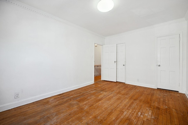 unfurnished bedroom featuring crown molding, baseboards, and hardwood / wood-style flooring