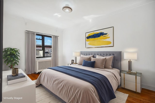 bedroom featuring radiator, crown molding, baseboards, and wood finished floors