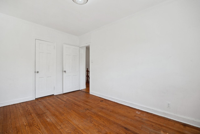 unfurnished bedroom featuring crown molding, baseboards, and wood finished floors